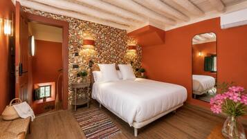 Un dormitorio con una cama grande, piso de madera, pared estampada y un espejo.