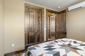 A bedroom with a bed, wooden wardrobe, and an air conditioning unit. - Beautiful 2-bedroom apartment in Sutherlin - Minutes from I-5! (Sutherlin)