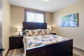 Un dormitorio con cama, mesitas de noche, una ventana y un cuadro colgado en la pared.