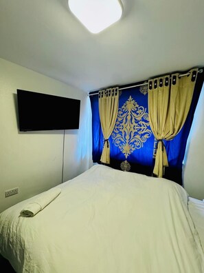 A room with a bed, a flat-screen TV mounted on the wall, and a window with curtains. - Unique Private Rooms Guesthouse (Bolton)