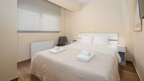 Habitación de hotel con una cama grande, una mesita de noche, un escritorio, una silla, un radiador y una ventana.