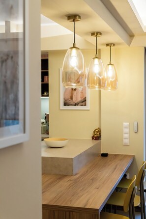 A modern kitchen with pendant lighting, a wooden dining table, and a framed picture on the wall. - Lush 3-bed - Parking - 500Mbps - Riviera (Paleo Faliro)