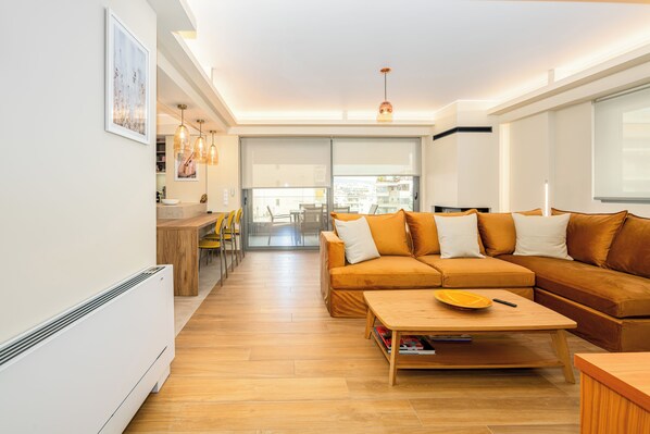 A modern living room with a sofa, coffee table, and dining area. - Lush 3-bed - Parking - 500Mbps - Riviera (Paleo Faliro)
