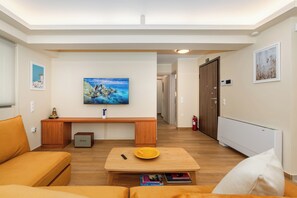 A living room with a sofa, a coffee table, a TV, and a painting on the wall. - Lush 3-bed - Parking - 500Mbps - Riviera (Paleo Faliro)
