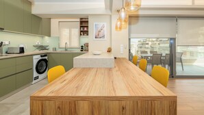 Una cocina moderna con una mesa de comedor de madera, sillas amarillas, una lavadora y un ventanal grande.