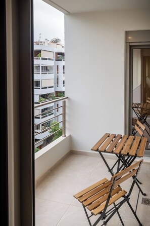 Ein Balkon mit Blick auf ein Gebäude, einem Holztisch und einem Stuhl.