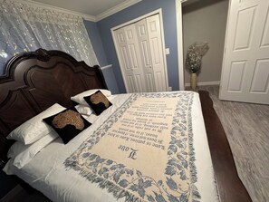 A bedroom with a bed, a wooden headboard, a white door, and a blue wall. - Spacious 6-bedroom house in quaint Graham with AC (Graham)