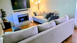 Un salon avec un canapé, un téléviseur, une cheminée et une lampe.
