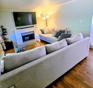 A living room with a sofa, a TV, a fireplace, and a lamp. - Spacious 6-bedroom house in quaint Graham with AC (Graham)