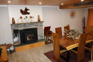 A cozy living room with a fireplace, wooden dining table, and chairs. - Spacious 6-bedroom house in quaint Graham with AC (Graham)