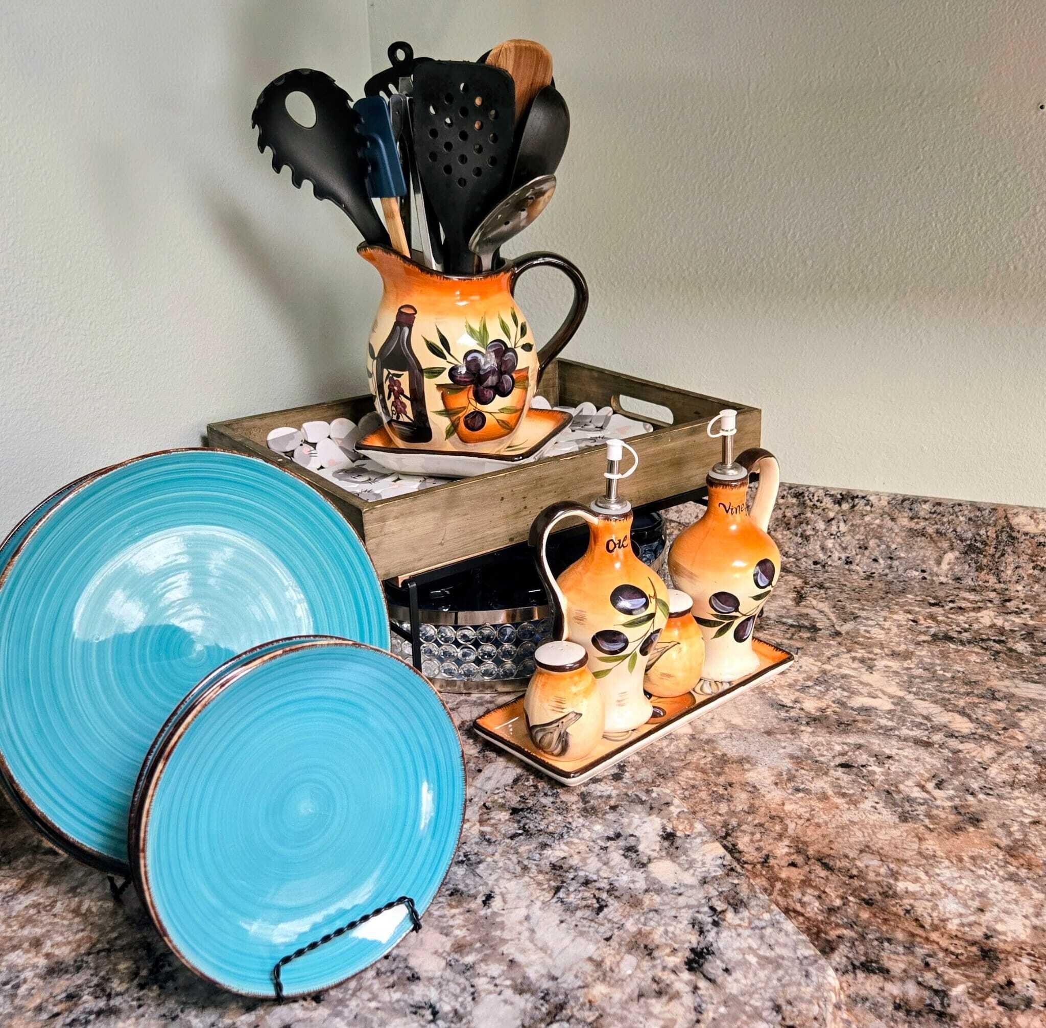 A kitchen counter with a tray holding a ceramic pitcher, two salt shakers, and a blue plate.