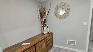 Une console en bois, agrémentée d’un miroir et de fleurs décoratives, est placée contre un mur de couleur claire.