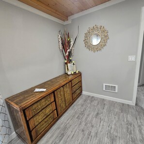 A wooden console with a mirror and decorative flowers against a light wall. - Spacious 6-bedroom house in quaint Graham with AC (Graham)