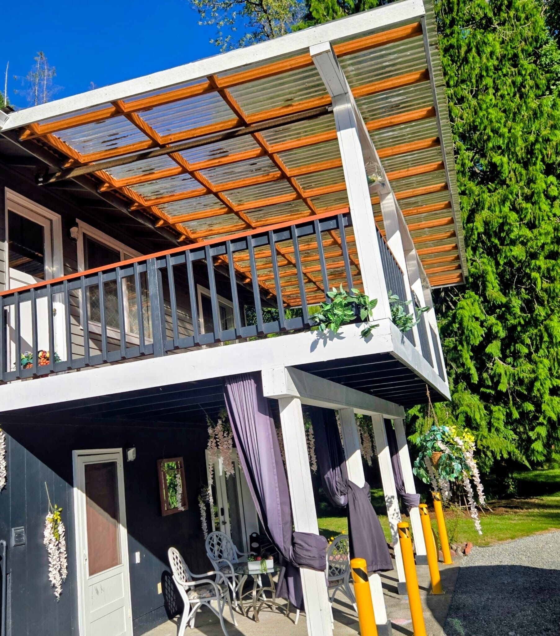 A two-story building with a balcony, outdoor seating, and a covered patio area.