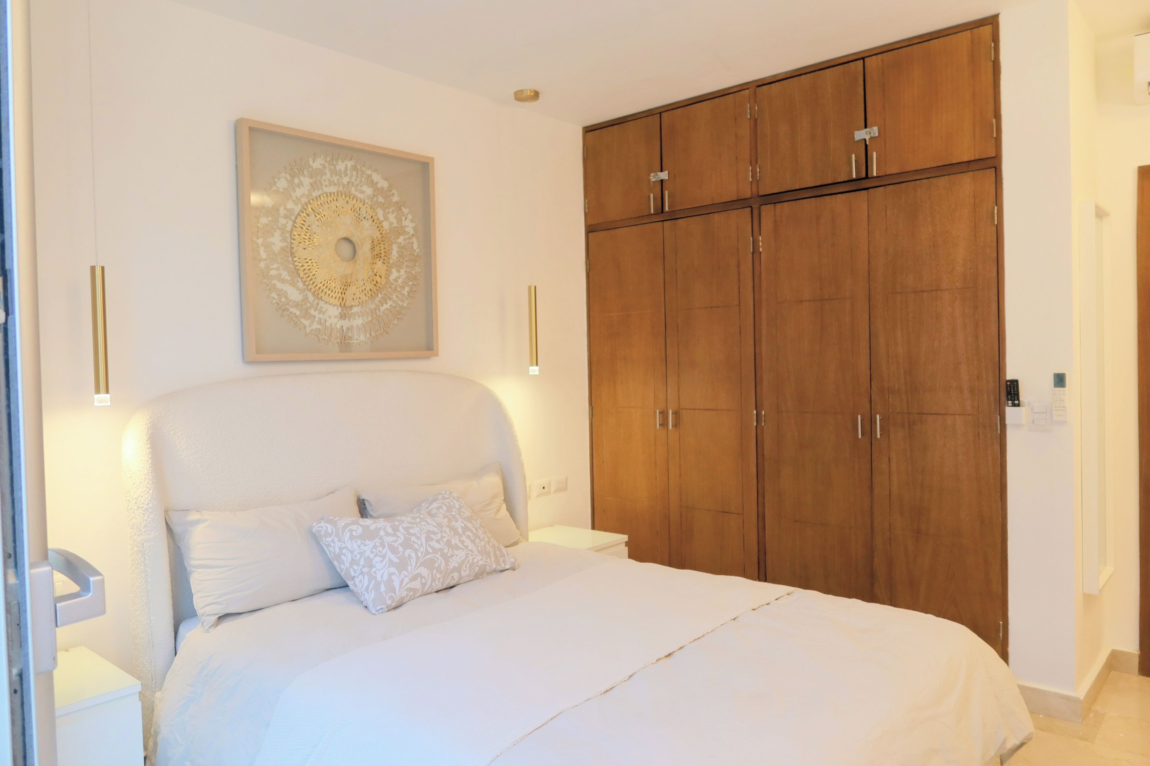 A bedroom with a large bed, a wardrobe, and a wall-mounted light fixture.