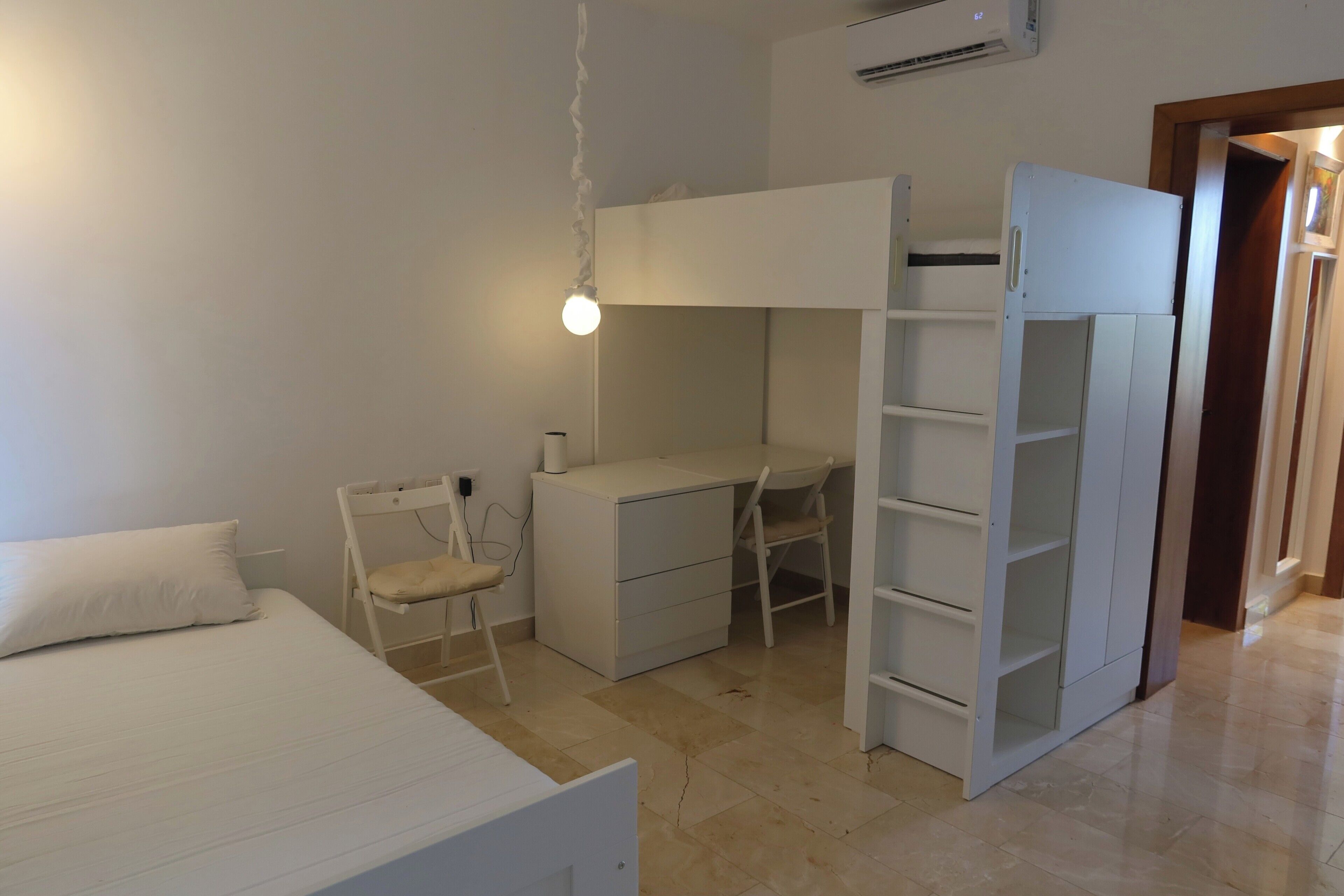 A bedroom with a bed, a desk, a chair, and a wardrobe.