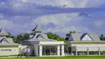 Un campo da golf con un club house caratterizzato da diversi edifici dagli stili architettonici differenti, tra cui un padiglione centrale con facciata in vetro.