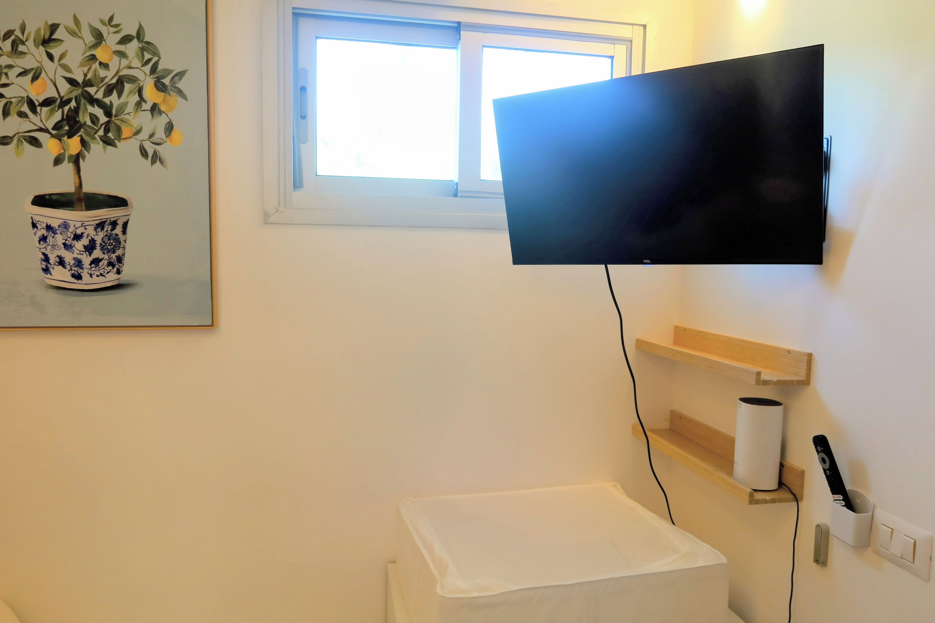 A bathroom with a white toilet, a white sink, a towel rack, a toilet paper holder, and a mounted television.