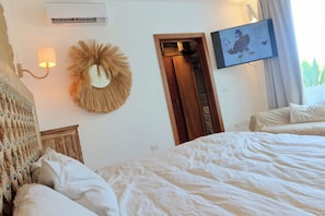 Ein Schlafzimmer mit einem Bett, einer Wandlampe, einem Spiegel, einer Tür und einem gerahmten Bild.