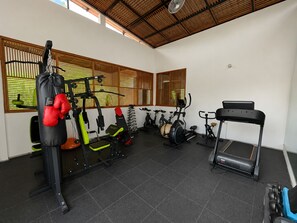 Un gimnasio con varios equipos de ejercicio, incluyendo un saco de boxeo, máquinas de pesas y equipos de cardio.