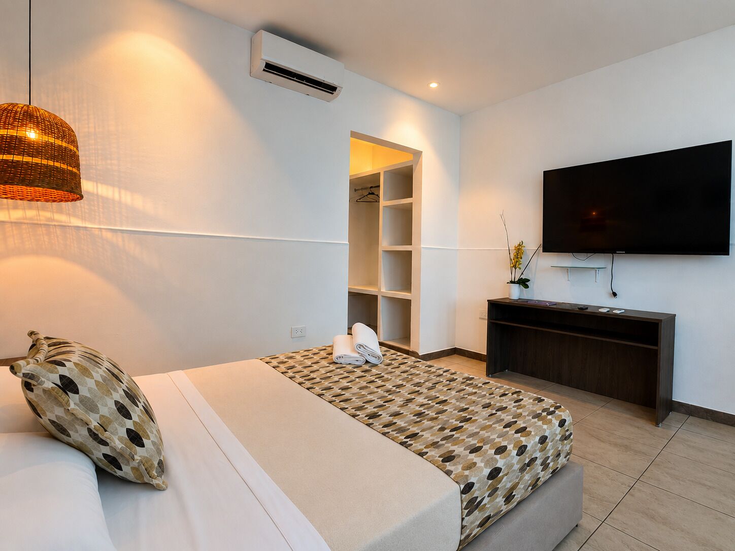 Ein modernes Hotelzimmer mit einem Bett, einem Fernseher, einem Kleiderschrank und einem kleinen Schreibtisch.