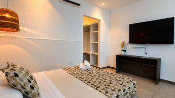 Ein modernes Hotelzimmer mit einem Bett, einem Fernseher, einem Kleiderschrank und einem kleinen Schreibtisch.