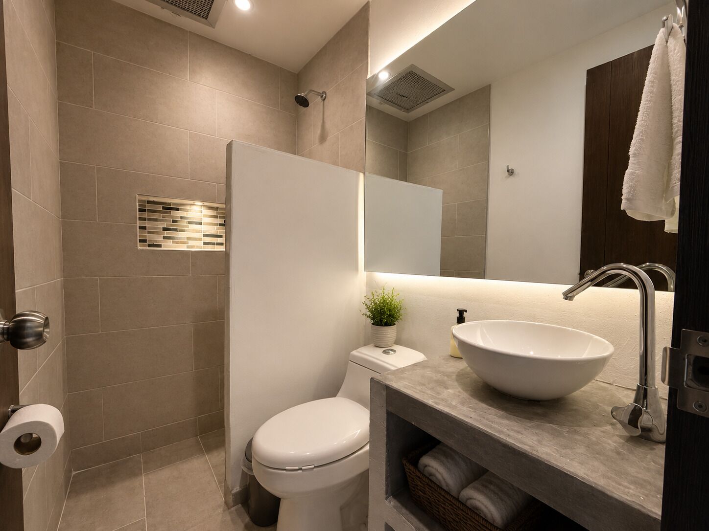 Un baño moderno con inodoro, bidé, lavamanos y espejo.