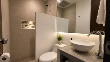 Un baño moderno con inodoro, bidé, lavamanos y espejo.