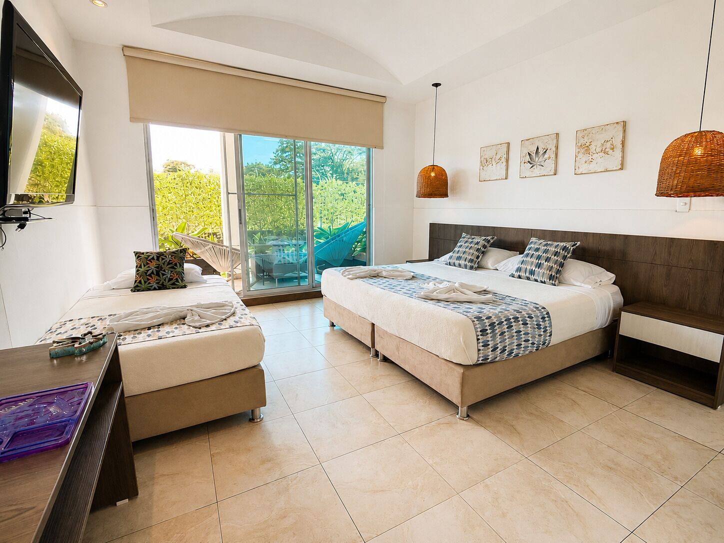 A modern bedroom with a large bed, a desk, and a balcony with glass doors.