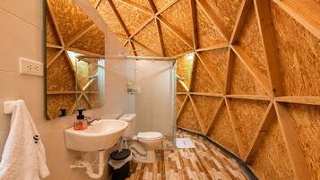 Une salle de bain avec un mur décoré de lambris en bois, un lavabo blanc, des toilettes et un miroir.