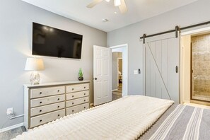 Une chambre à coucher avec un lit, une commode, un téléviseur et une porte coulissante.