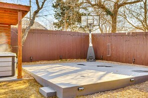 A backyard with a hot tub, a wooden deck, and a basketball hoop. - Sauna, Hot Tub & Backyard Fun in OKC (Oklahoma City)