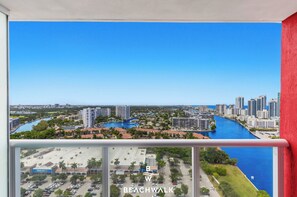 A balcony with a view of a cityscape, including a marina and high-rise buildings. - High Floor Studio w Resort Living & Beach (Hallandale Beach)