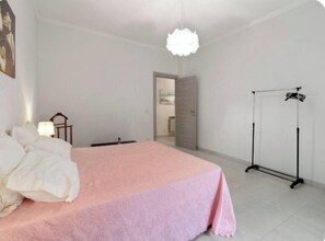 Une chambre à coucher avec un lit, une lampe sur pied, une porte et un portant à vêtements.