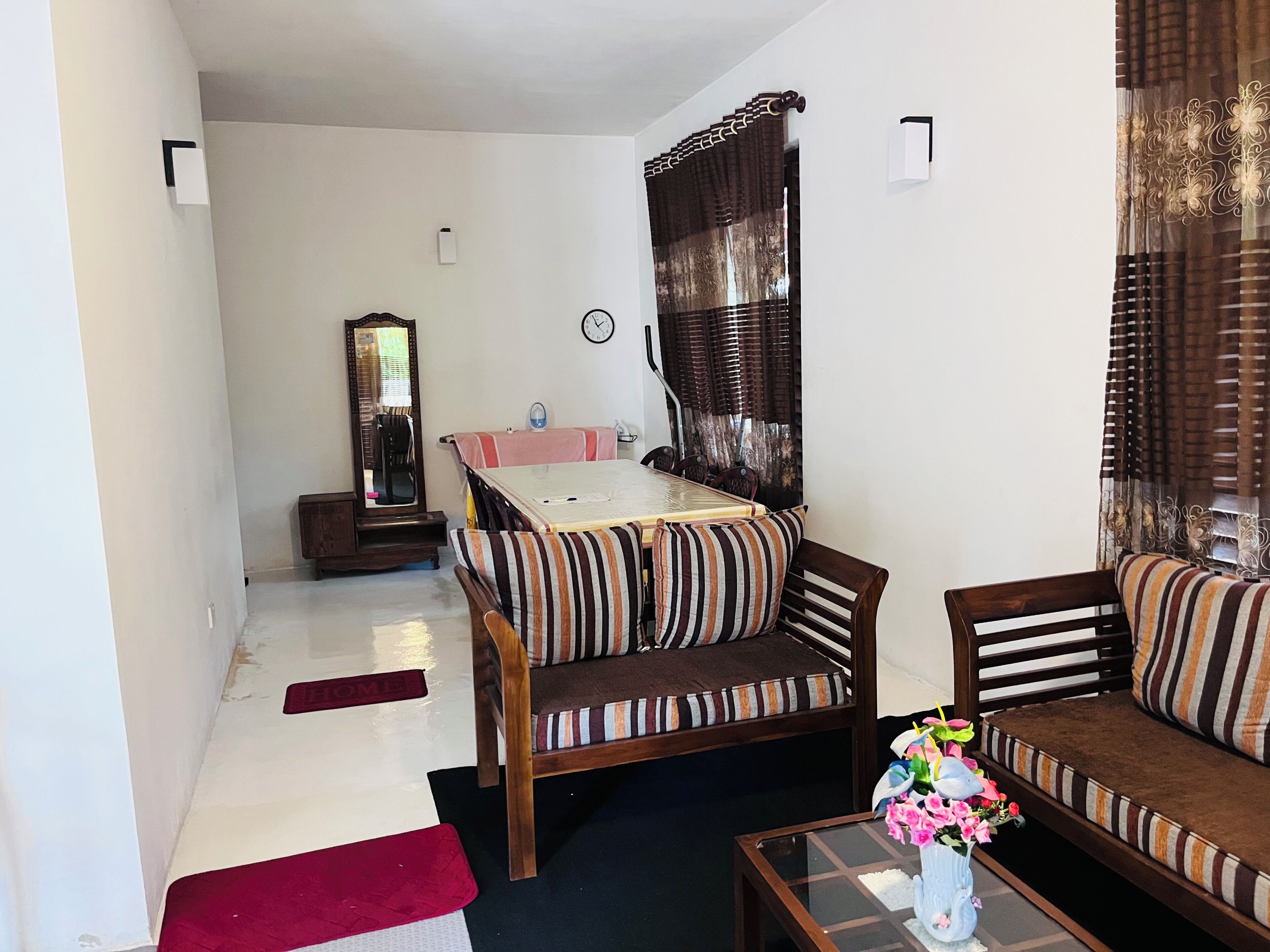 A furnished living room with a sofa, armchair, and a small table with a vase of flowers.