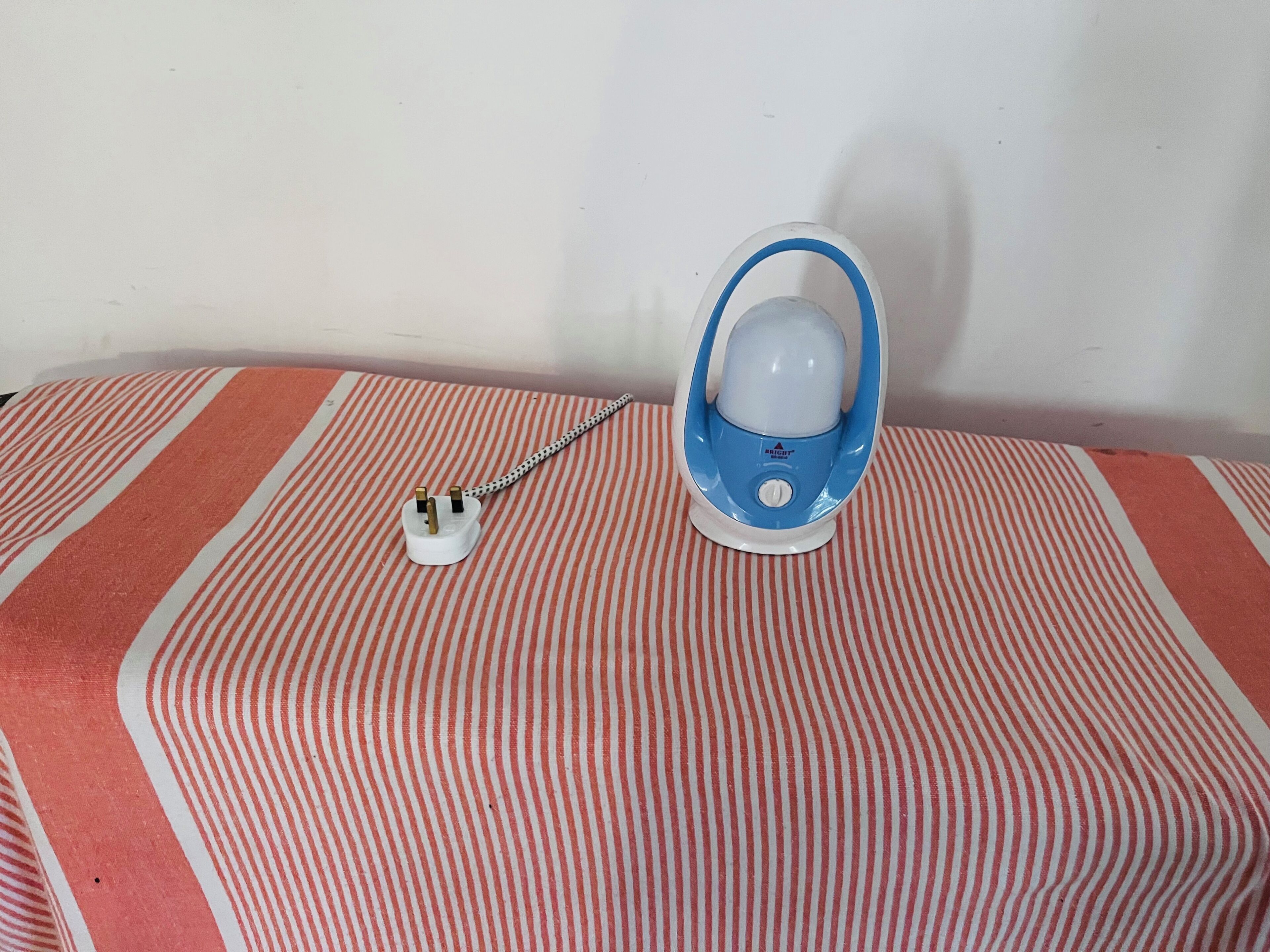 A blue and white electric kettle on a striped tablecloth.