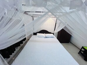 Een kamer met een bed onder een hemelbed, een houten hoofdeinde en een klein krukje.