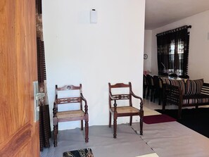 Een kamer met twee houten stoelen, een eettafel met stoelen en een rood vloerkleed.