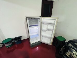Een compacte koelkast met verschillende planken, in een kamer met een rode vloer.