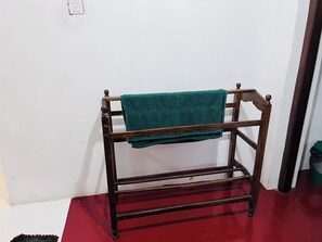 A wooden bench with a green towel draped over it, positioned against a white wall.