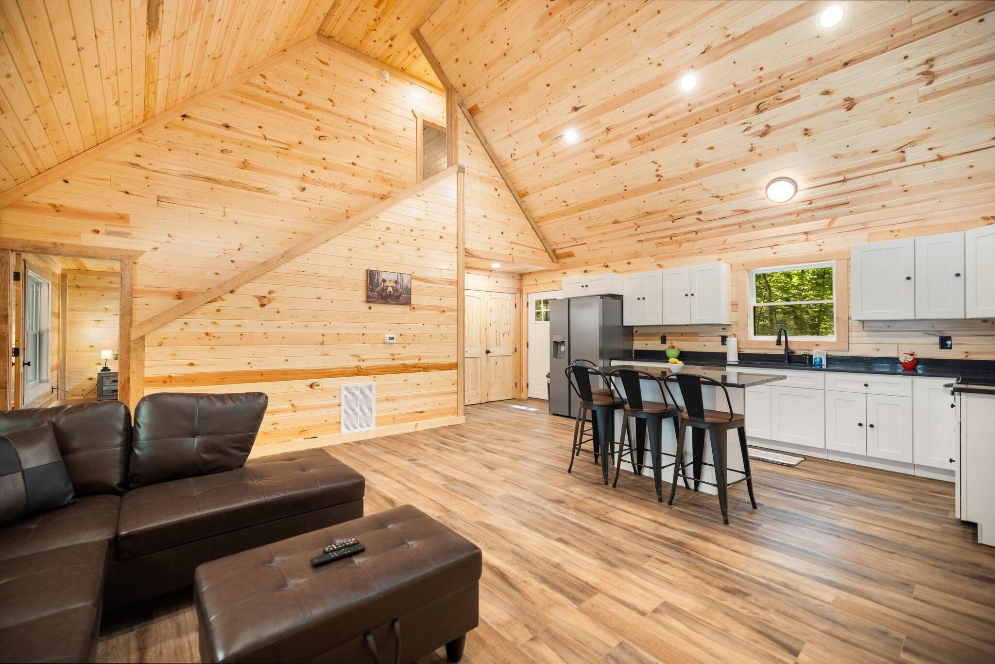 A log cabin interior with a living area, kitchen, and dining space.