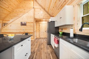 A wooden interior with a kitchen area, including cabinets, a refrigerator, and a sink.