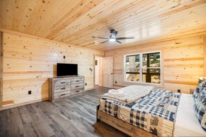 Ein Zimmer mit einem Bett, einem Schminktisch, einem Fernseher und einem Deckenventilator.