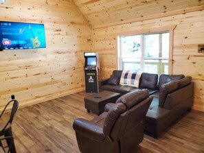 A room with a wooden interior, a leather sofa, a massage chair, a massage table, and a gaming console.