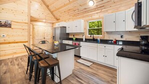 L’intérieur d’un chalet en bois comprend une cuisine, un coin repas et des tabourets de bar.