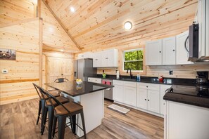 Ein Holzblockhaus-Innenraum mit Küche, Essbereich und Barhocker.