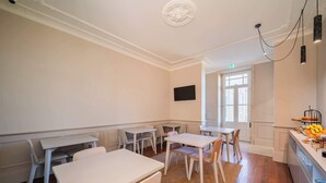 Ein Zimmer mit weißen Wänden, einem an der Wand befestigten Flachbildfernseher und einer Küchenzeile mit Obstauslage.