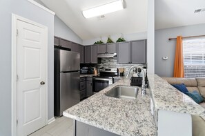 A modern kitchen with grey cabinets, stainless steel appliances, and a granite countertop. - Cowboy pool Hot tub Boho Charlotte (Charlotte)
