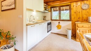 A kitchen with white cabinets, a sink, a window, and a clock on the wall. - Androsace - VAL CENIS (VAL CENIS)