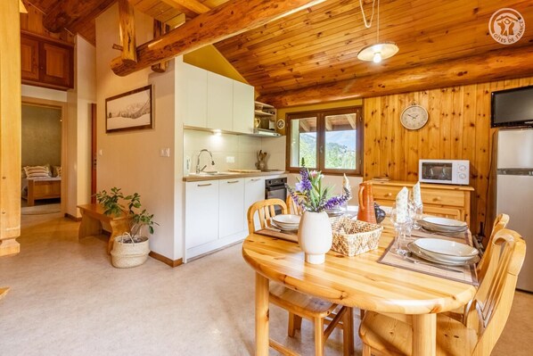 Et træinteriør med et spiseområde, et køkken og udsigt til det fri.